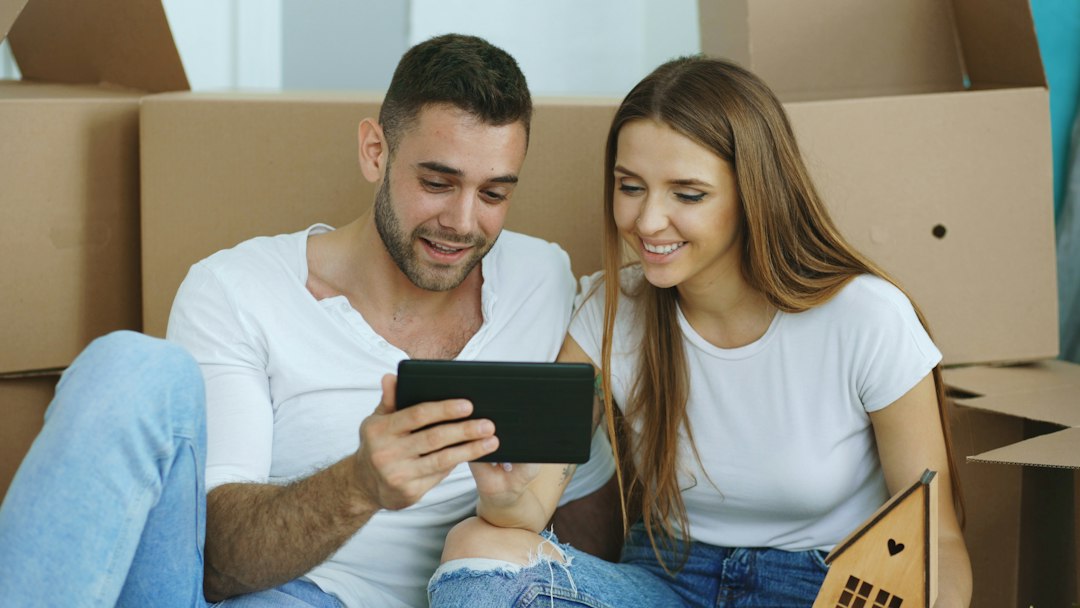 Home Young couple sitting on floor using tablet computer after reloction in their new house
